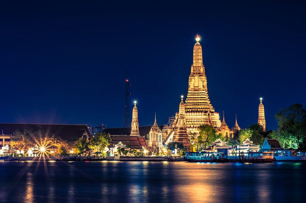 Verlichte Wat Arun-tempel aan de Chao Phraya-rivier in Bangkok tijdens de avond.