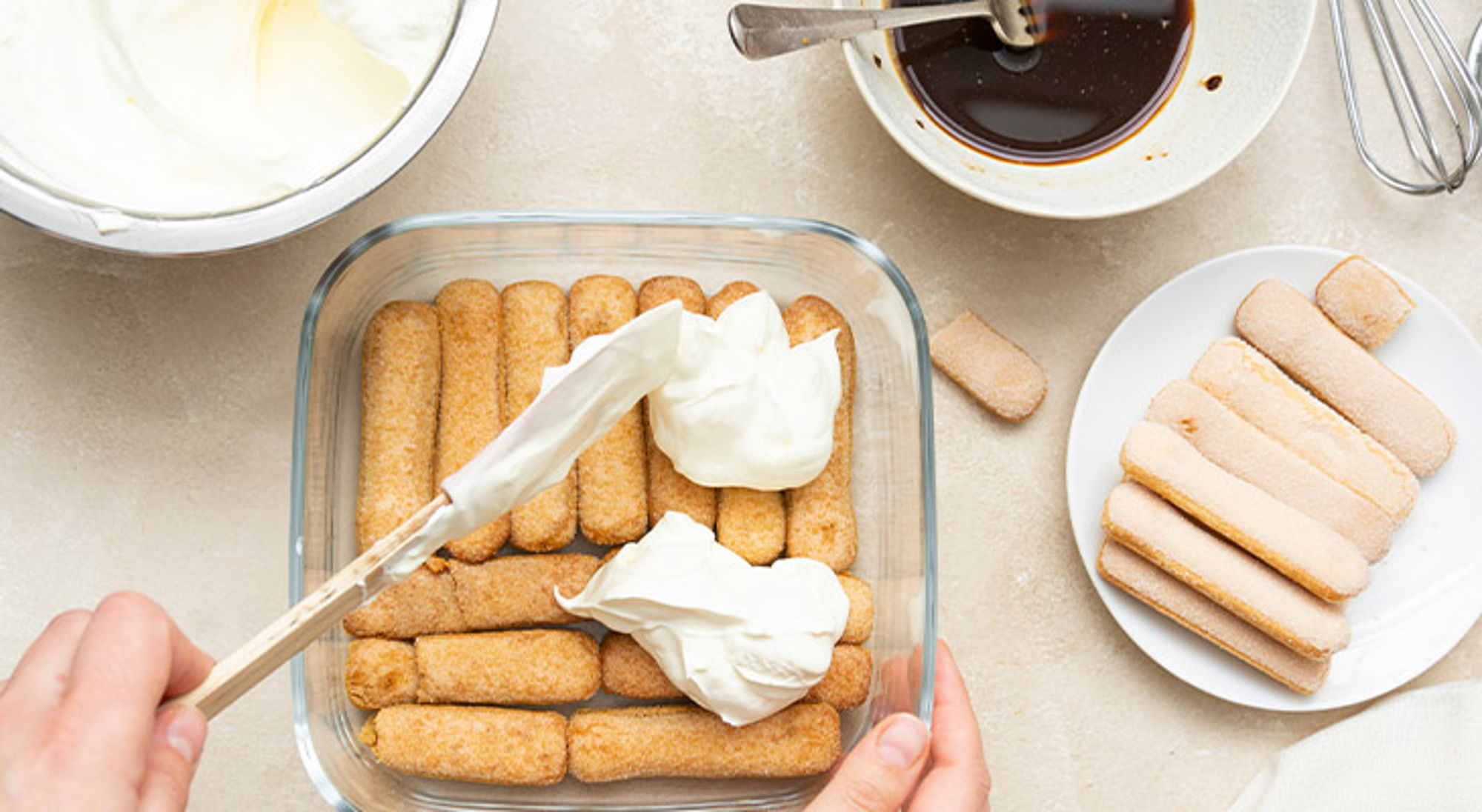 Tiramisu maken Tiramisu bereiden met lange vingers, mascarponecrème en espresso in een ovenschaal.