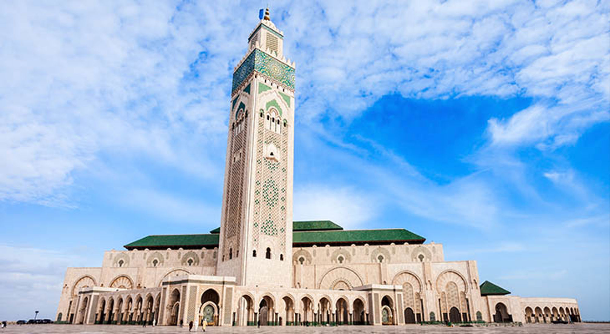 Hassan II moskee Hassan II-moskee in Casablanca, Marokko, met hoge minaret en mozaïekdetails onder een blauwe lucht.