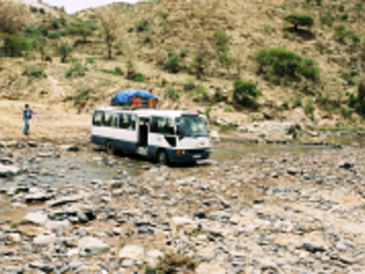 Bus op de Route Ethiopië 29 dagen steekt een rotsachtige rivierbedding over.