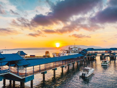 Zonsondergang bij de veerhaven met pier en boten tijdens de route Java en Bali.
