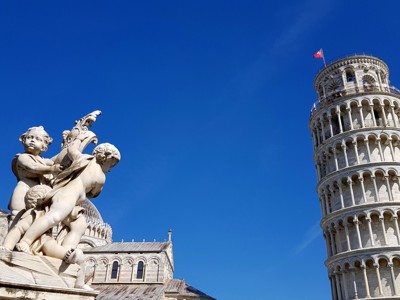 Scheve Toren van Pisa naast marmeren beeldhouwwerk op het Piazza dei Miracoli, Italië.