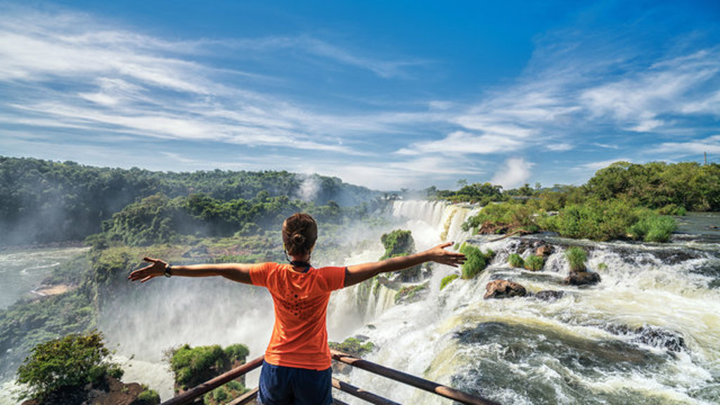 Reiziger met gespreide armen bij de Iguazú-watervallen tijdens een 22-35ers reis Brazilië.