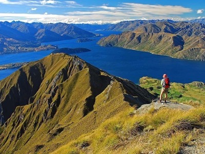 Wandelaar op bergtop met uitzicht op Lake Wanaka en de Zuidelijke Alpen, Route Nieuw-Zeeland.