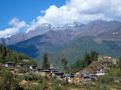 Uitzicht op een Bhutaans bergdorp met Himalayapieken op de achtergrond tijdens de route Sikkim en Bhutan.