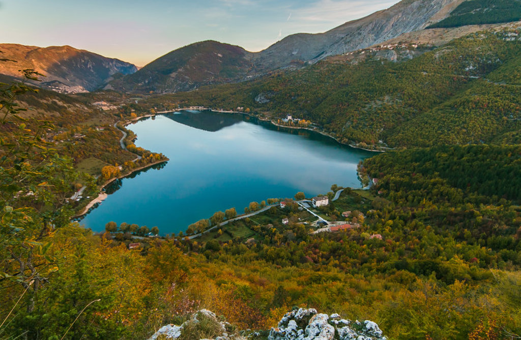 Uitzicht op een bergmeer in de Centrale Apennijnen, Italië, omringd door beboste hellingen en bergen.