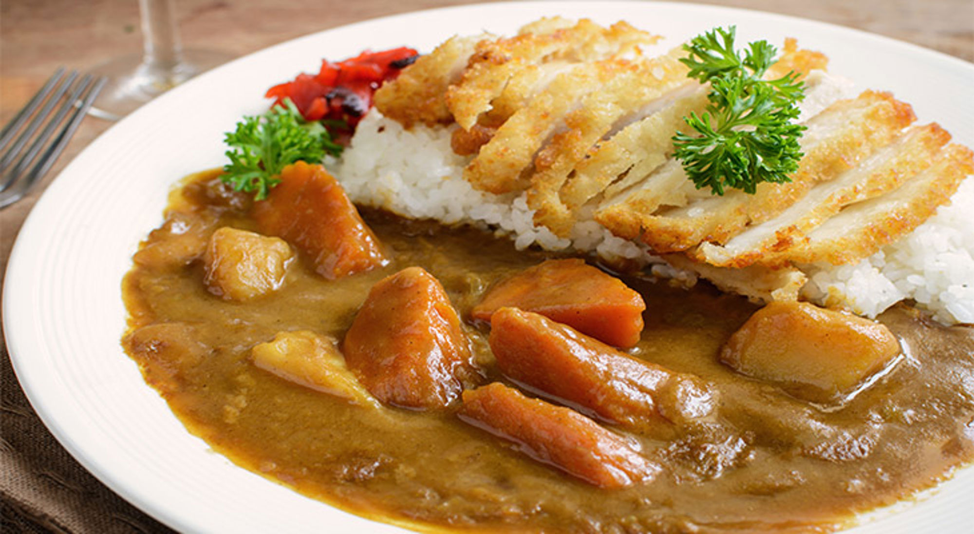 Japanse curry Japans curry gerecht met krokante schnitzel, rijst en groenten op een bord.