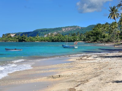Tropisch strand in Cuba met palmbomen, helderblauwe zee en vissersbootjes voor de kust.