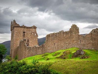 Ruïne van Urquhart Castle aan Loch Ness in de Schotse Hooglanden onder een bewolkte lucht.
