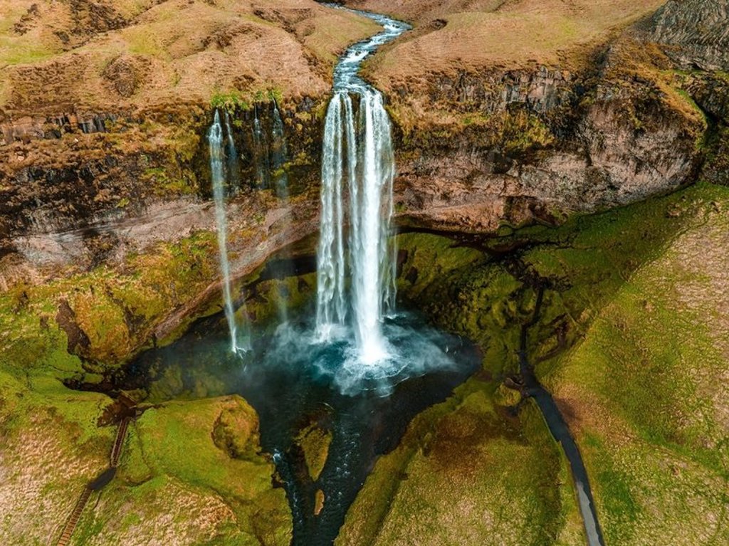 Waterval in een groen, rotsachtig landschap in IJsland tijdens een groepsrondreis.