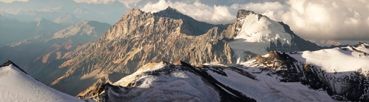 Besneeuwde bergtoppen van de Aconcagua in de Andes, Argentinië, onder een dramatische wolkenlucht.