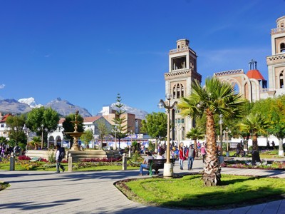 Plaza de Armas in Huaraz met fontein en kerk, met besneeuwde toppen van de Cordillera Blanca op de achtergrond.