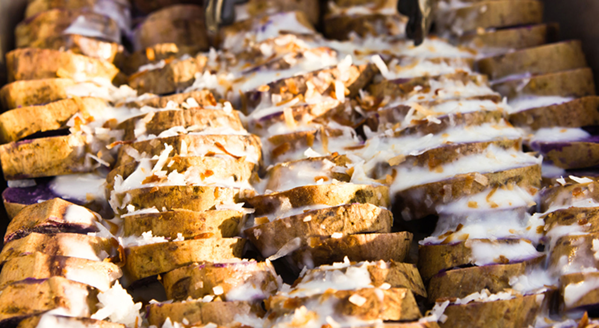 Plakjes zoete aardappel met kokosmelk en geraspte kokos, close-up.