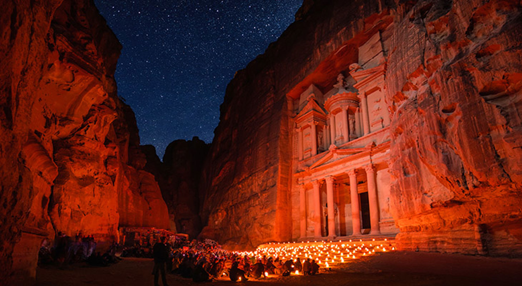 jordanie-petra Verlichte rotsgevel van de Schatkamer in Petra tijdens een nachtshow met kaarsen onder een sterrenhemel.