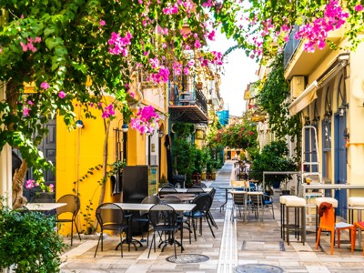 Sfeervol straatje in Griekenland met terrasjes en bloeiende bougainvillea, ideaal voor een familiereis.