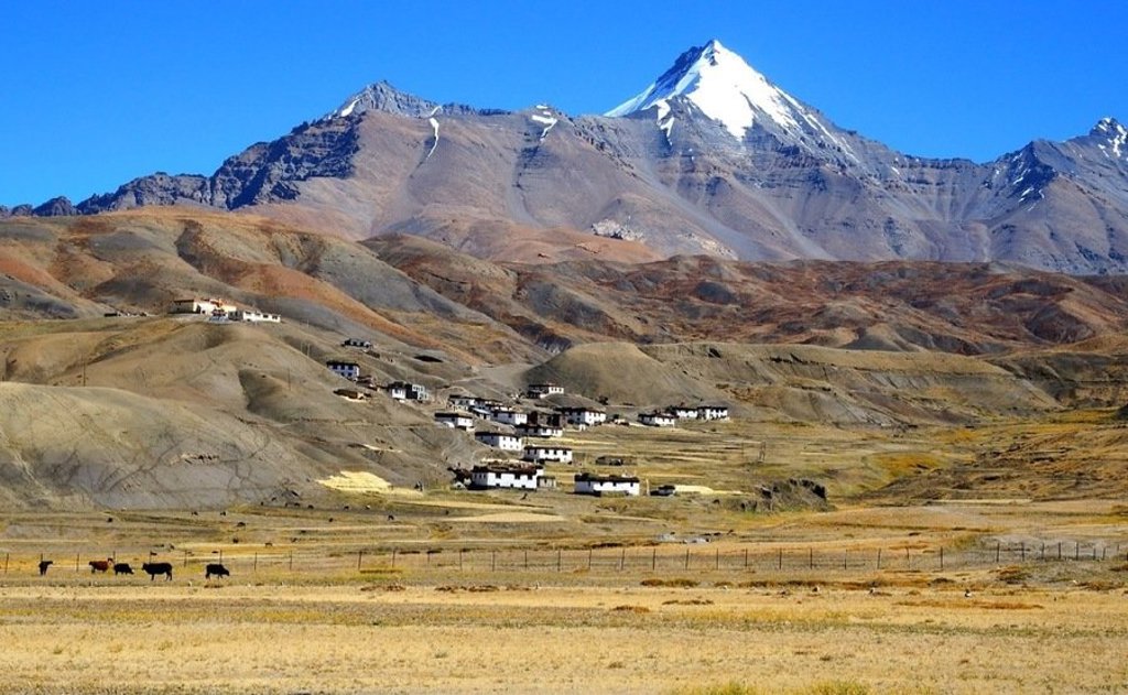 Wandelaars bij een stoepa met besneeuwde bergtoppen in Ladakh, India.