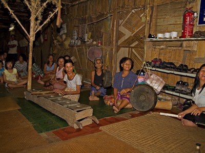 Lokale bewoners in een longhouse op Maleisisch Borneo tijdens de familiereisroute, met traditionele muziekinstrumenten.