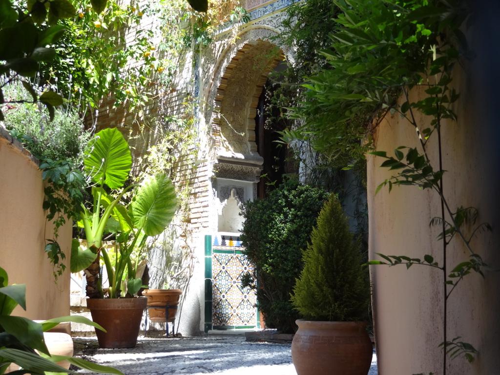 Sfeervolle patio met Moorse boog en kleurrijke tegels in Andalusië, Spanje.