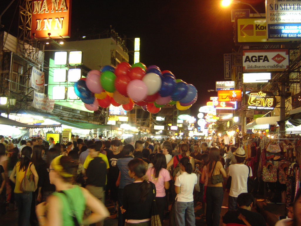Drukke avondmarkt in Bangkok met neonreclames en kleurrijke ballonnen tijdens een groepsrondreis Thailand Noord en Zuid.