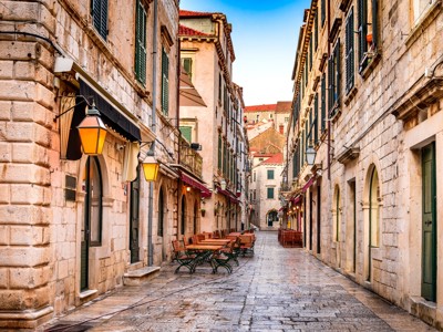 Smalle straat met historische stenen gebouwen en terrassen in Dubrovnik, stop op de Route Balkan rondreis.