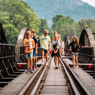 Kinderen wandelen over de River Kwai-brug in Thailand tijdens de familiereis Thailand Hoogtepunten.