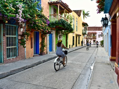 Fietsen door kleurrijke straat met bloemen en balkons in Cartagena, Colombia, tijdens Route Colombia.