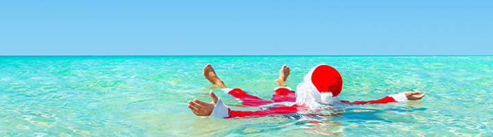Kerstman drijft ontspannen in helderblauw zeewater tijdens de kerstvakantie.