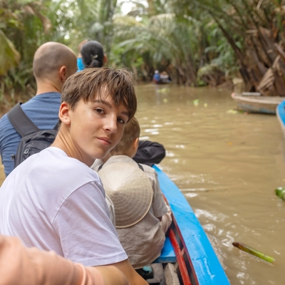 Gezin in een bootje op de Mekongdelta tussen palmen tijdens de Familiereis Vietnam Kort.