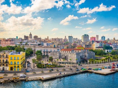 Skyline van Havana met fort aan de kust en kleurrijke gebouwen onder een blauwe lucht.