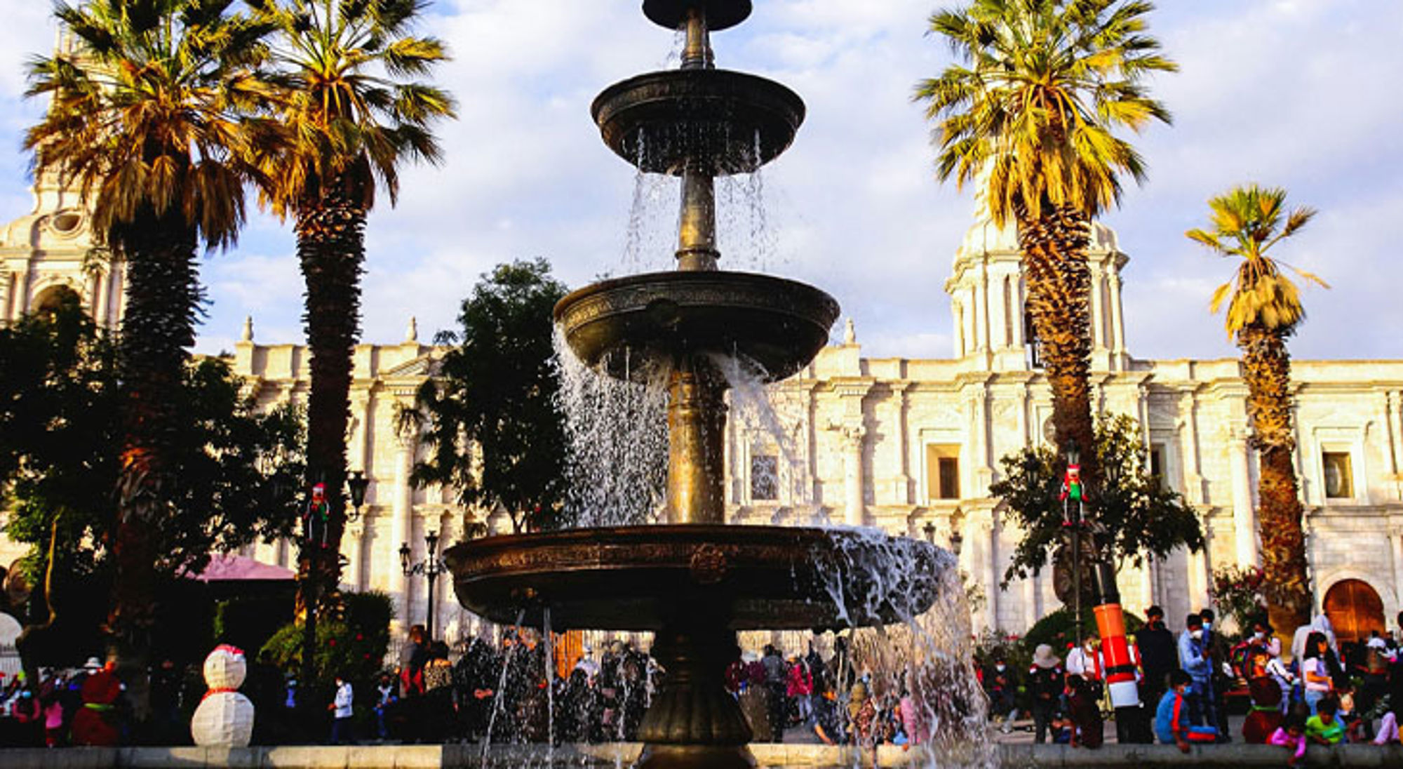 Fontein op Plaza de Armas in Arequipa, met palmbomen en de kathedraal op de achtergrond.