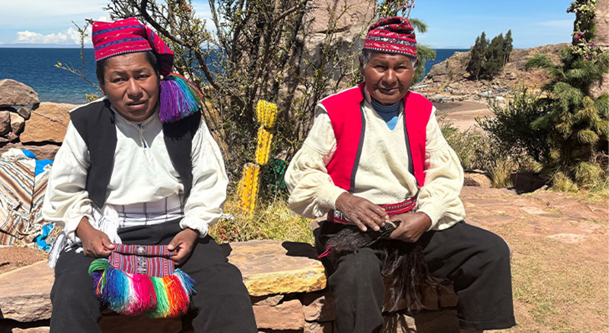 Peru Twee locals in traditionele kleding op een rots met uitzicht op het Titicacameer.