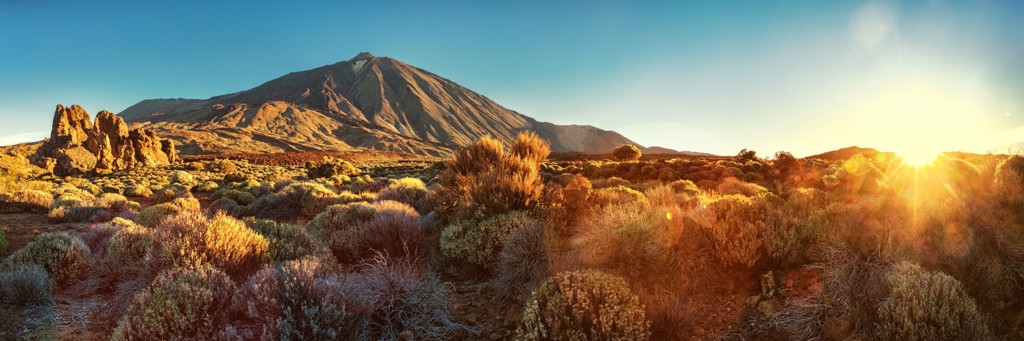 Zonsondergang bij de Teide-vulkaan op Tenerife, met ruig vulkaanlandschap en struikgewas.