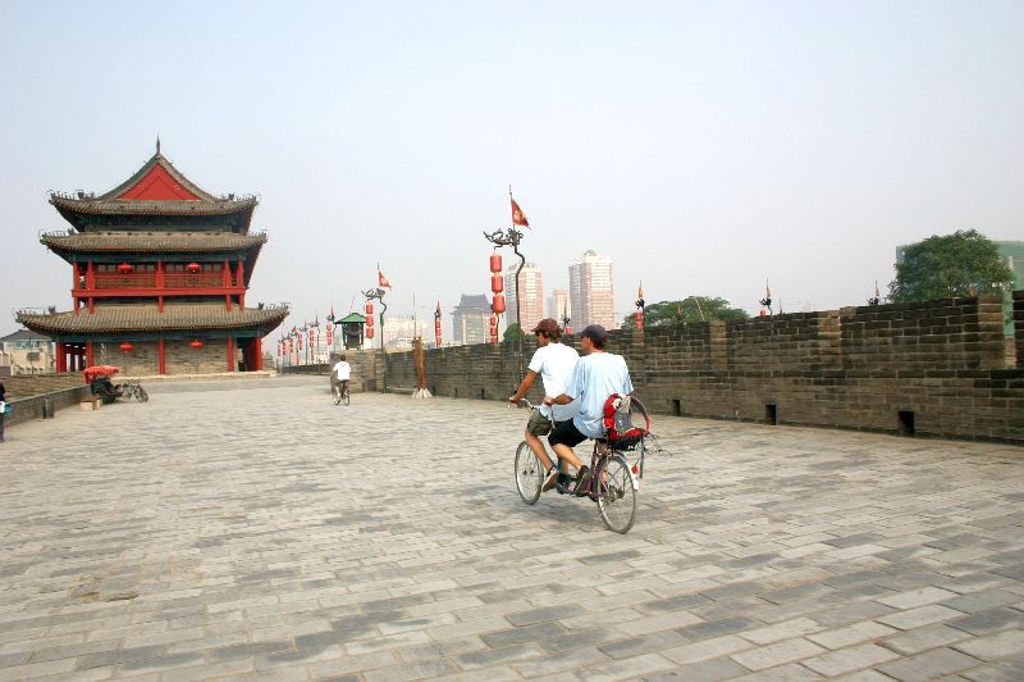 Fietstocht over de stadsmuur bij een traditionele Chinese poort tijdens een familiereis China.