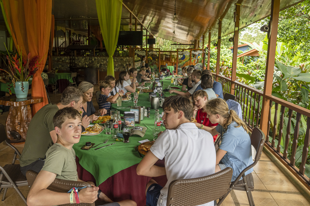 Gezin eet samen in een openluchtrestaurant in de jungle tijdens een familiereis Costa Rica.