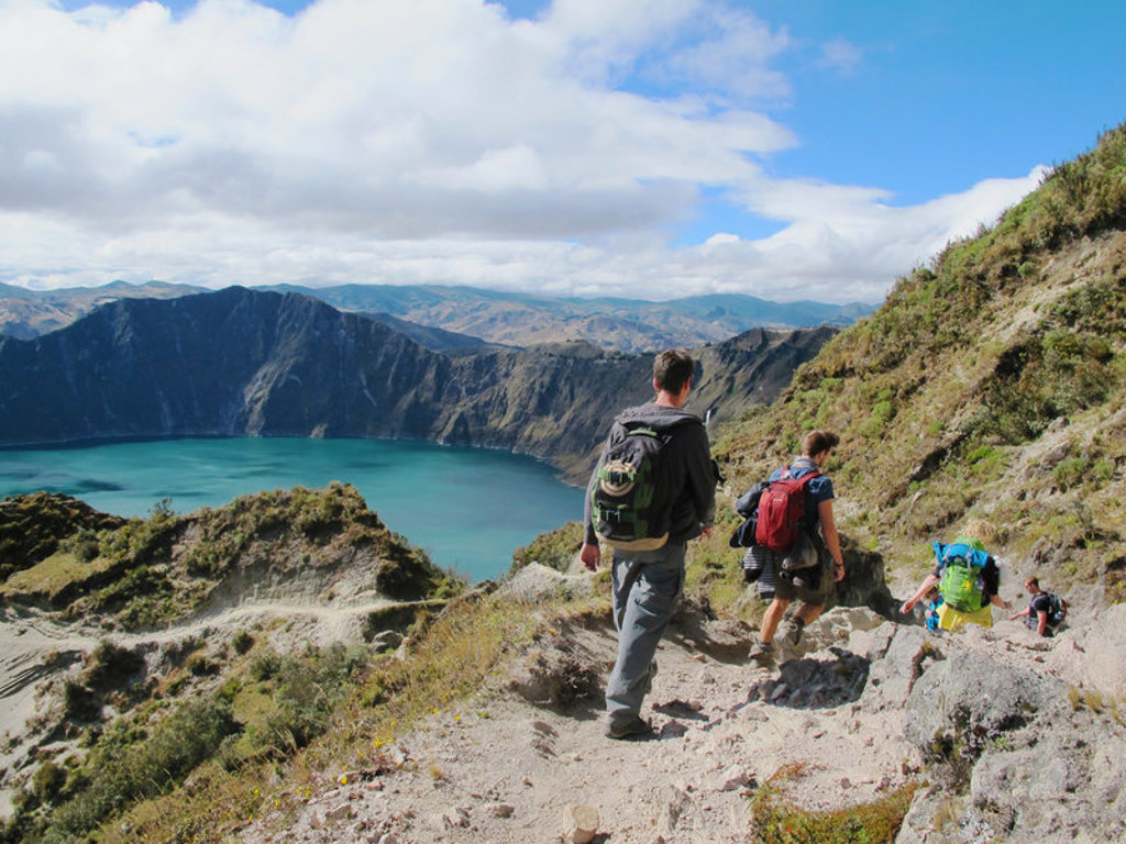 Wandelaars dalen af langs de Quilotoa-krater met uitzicht op het turquoise kratermeer in Ecuador.