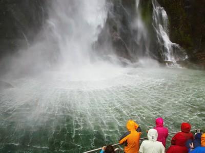 Reizigers op een boot bij een krachtige waterval in Nieuw-Zeeland tijdens de Route Nieuw-Zeeland.