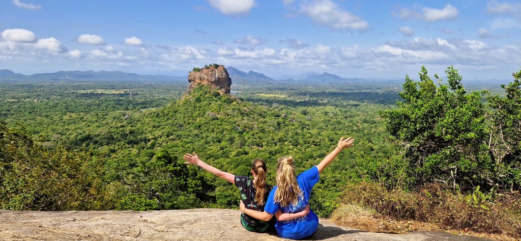 Twee reizigers kijken uit over Sigiriya-rots en het groene landschap tijdens een 22-35ers reis in Sri Lanka.