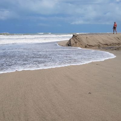 Wandelaars op het strand bij de monding van een rivier tijdens de dagtocht Taironaka.