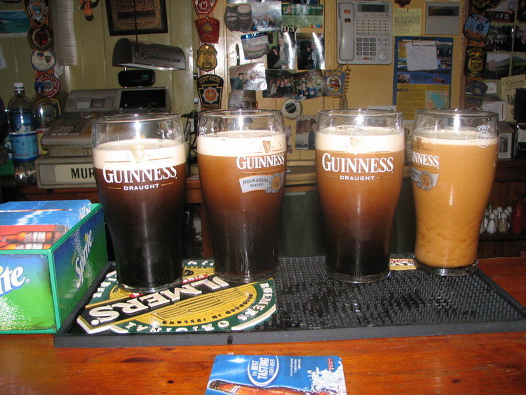 Pinten Guinness op de bar in een Ierse pub tijdens een groepsrondreis door Noord-Ierland en Ierland.