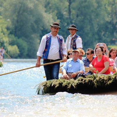 Toeristen varen met een houten raft over de Dunajec rivier, begeleid door twee gidsen met roeispanen.