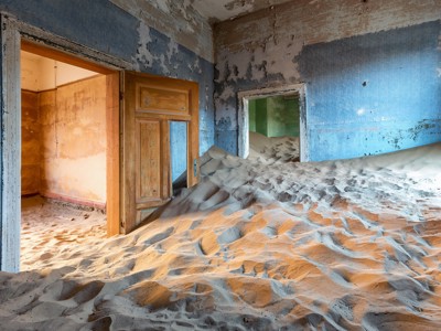 Verlaten huis in Kolmanskop, Namibië, met zandduinen die de kamers hebben gevuld.