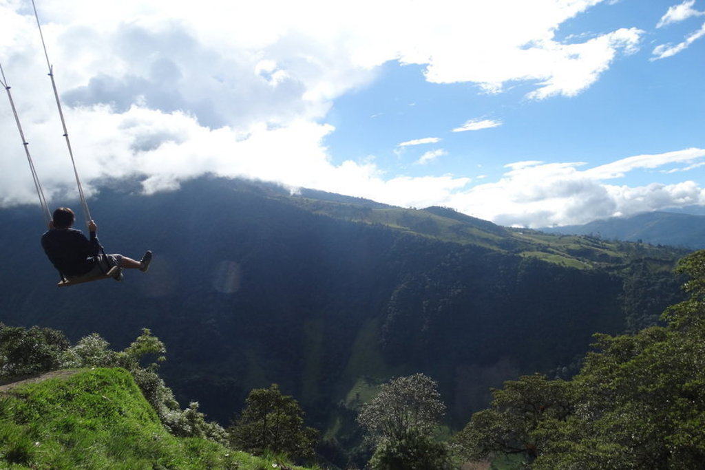 Reiziger op een schommel met uitzicht op groene bergen in Ecuador tijdens familiereis Ecuador en Galapagos.