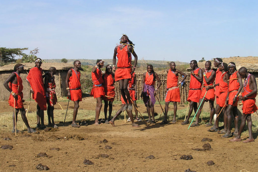 Maasai-krijgers in rode kledij voeren een traditionele springdans uit in Kenia tijdens Familiereis Kenia Comfort.