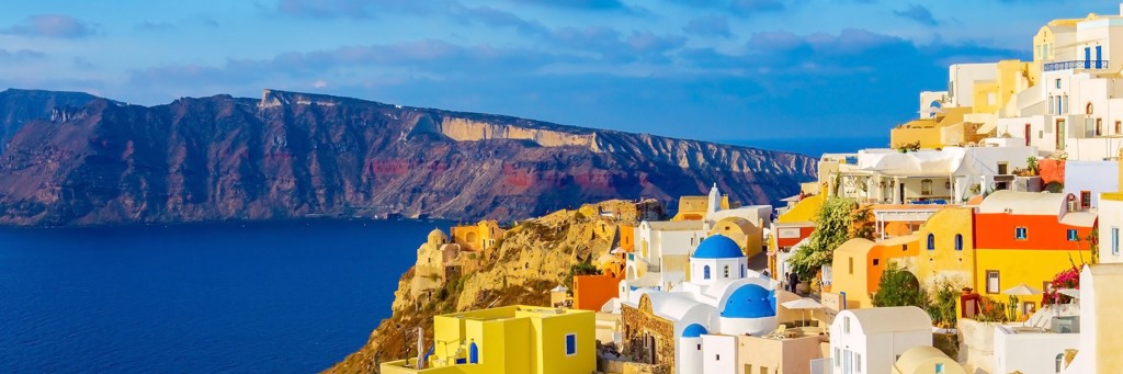Witte huizen en blauwe koepels in Oia op Santorini, met uitzicht op de caldera en zee in Griekenland.