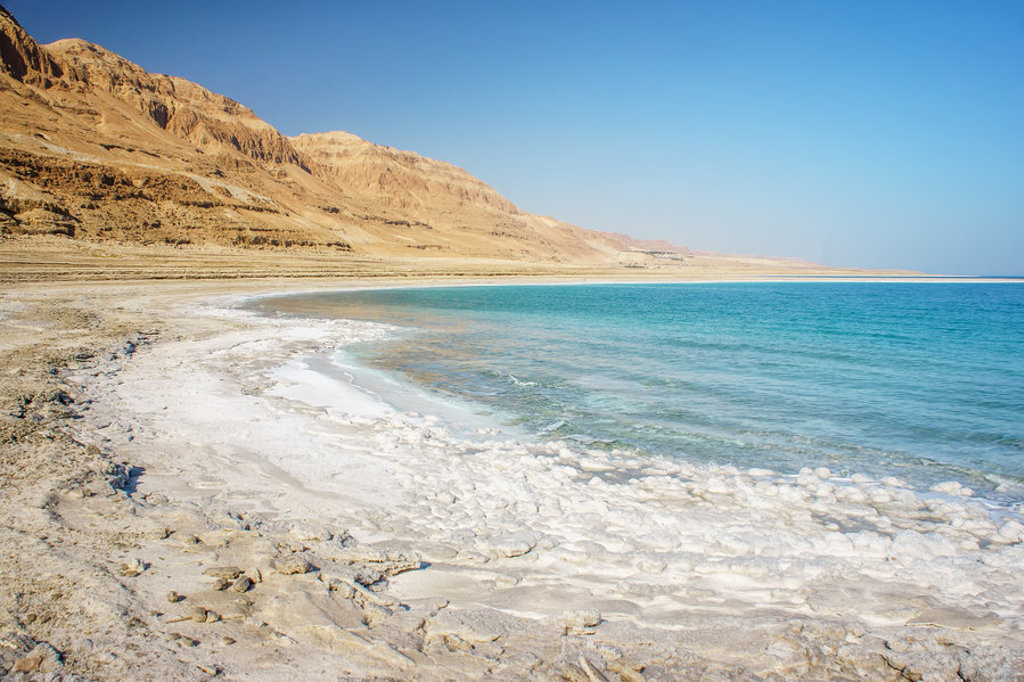 Kustlijn van de Dode Zee met zoutafzettingen en woestijnbergen tijdens groepsrondreis Israël en Jordanië.