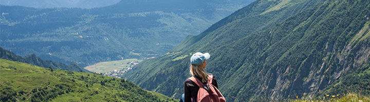 Wandelaar met rugzak kijkt uit over de groene bergen en valleien van Georgië.