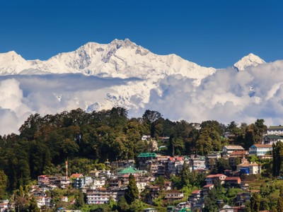 Stadszicht op Darjeeling met besneeuwde Himalaya-bergtoppen op de achtergrond.