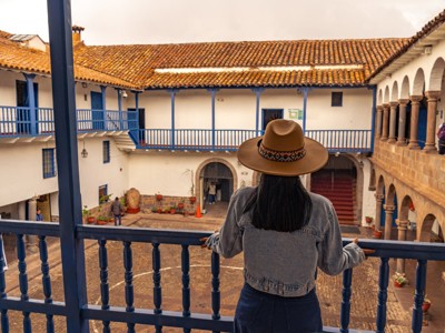 Uitzicht vanaf balkon op koloniale binnenplaats met bogen en blauwe balkons in Cusco, Peru.