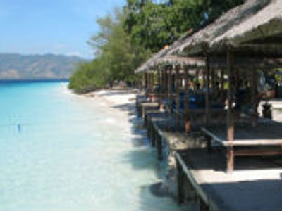 Strand aan Lombok met palapa’s op houten vlonders langs helderblauw zeewater.
