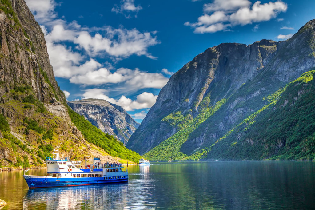 Cruiseboot op een fjord tussen steile bergen tijdens groepsrondreis Scandinavië.